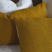 close-up of woven mustard yellow pillow on patterned fabric