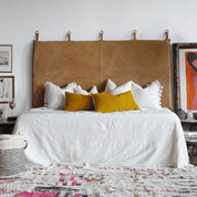 yellow pillows styled on white bedding with tan leather headboard