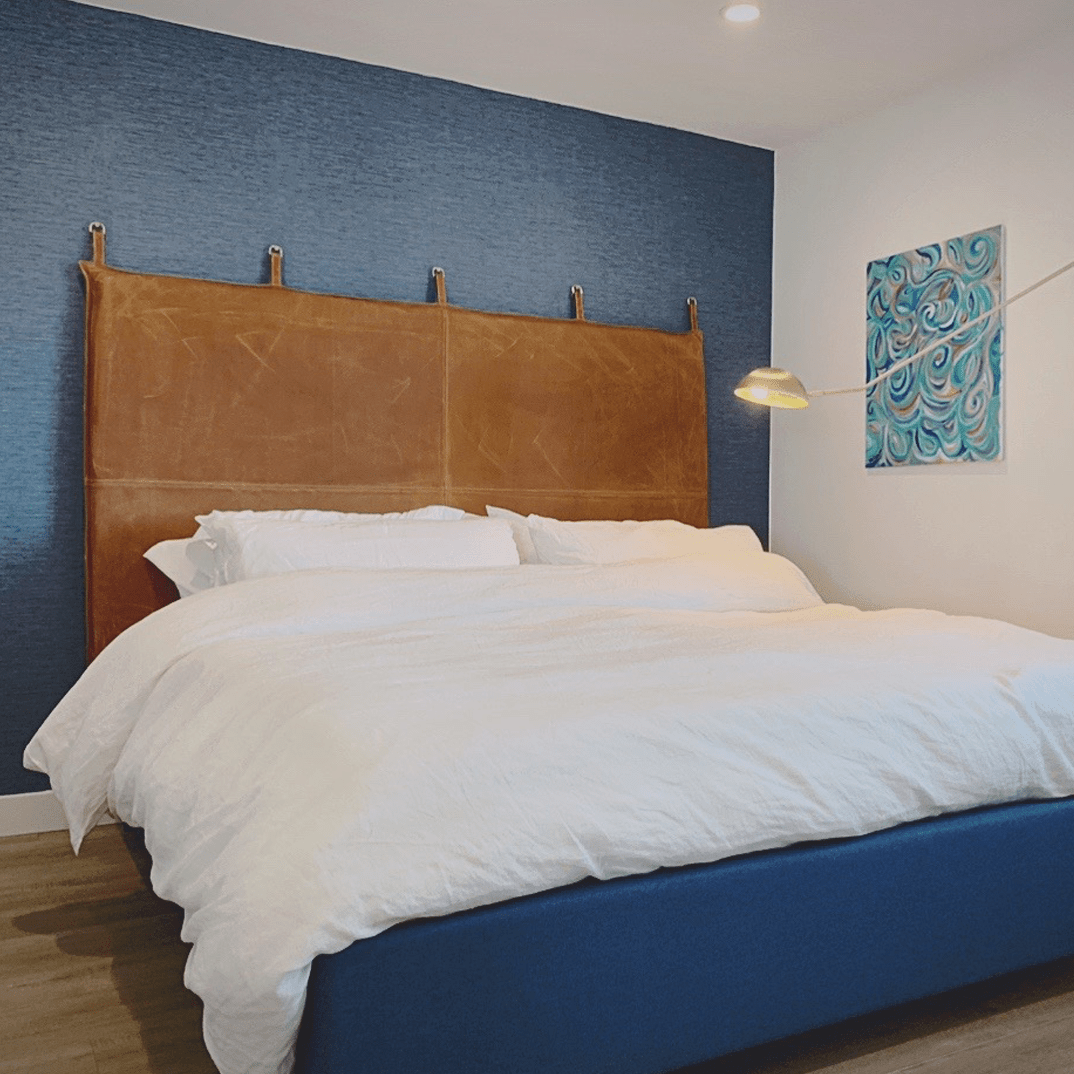 modern bedroom with a blue wall and brown leather headboard and artowork on the wall