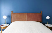 Whiskey leather hanging headboard on blue wall