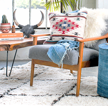 southwestern patterned decorative throw pillow sitting on a grey chair with a vintage african indigo blanket in a loft