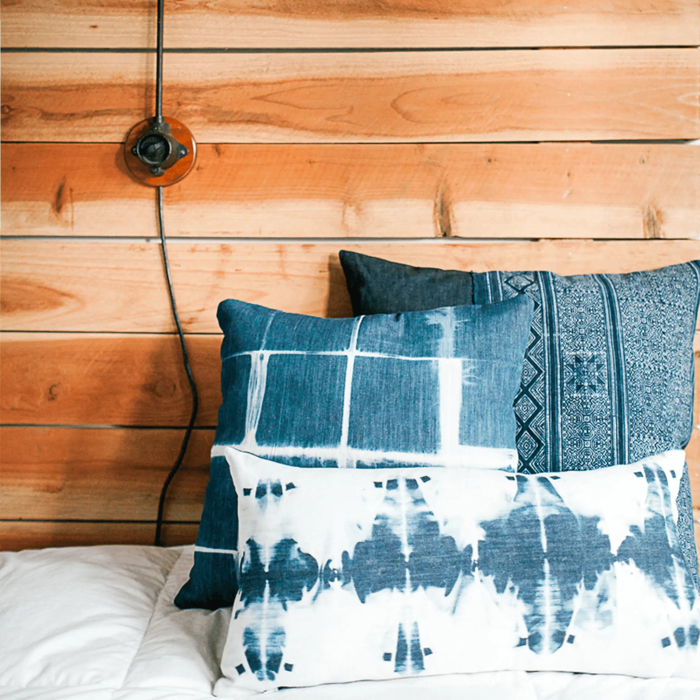 blue and white tie dye pillows sitting on bed with wood background