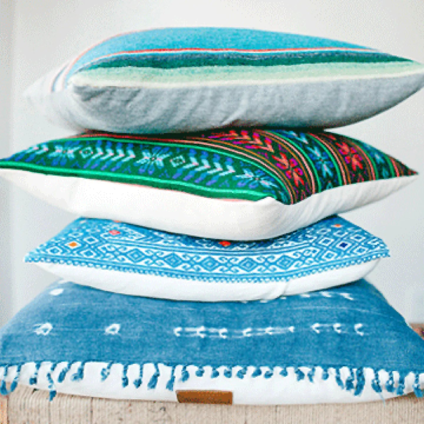 stack of blue and white decorative throw pillows sitting on top of a bench
