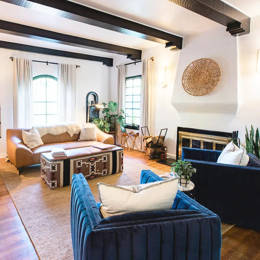 southwestern living room setting with blue velvet chairs and custom ottoman next to a fireplace