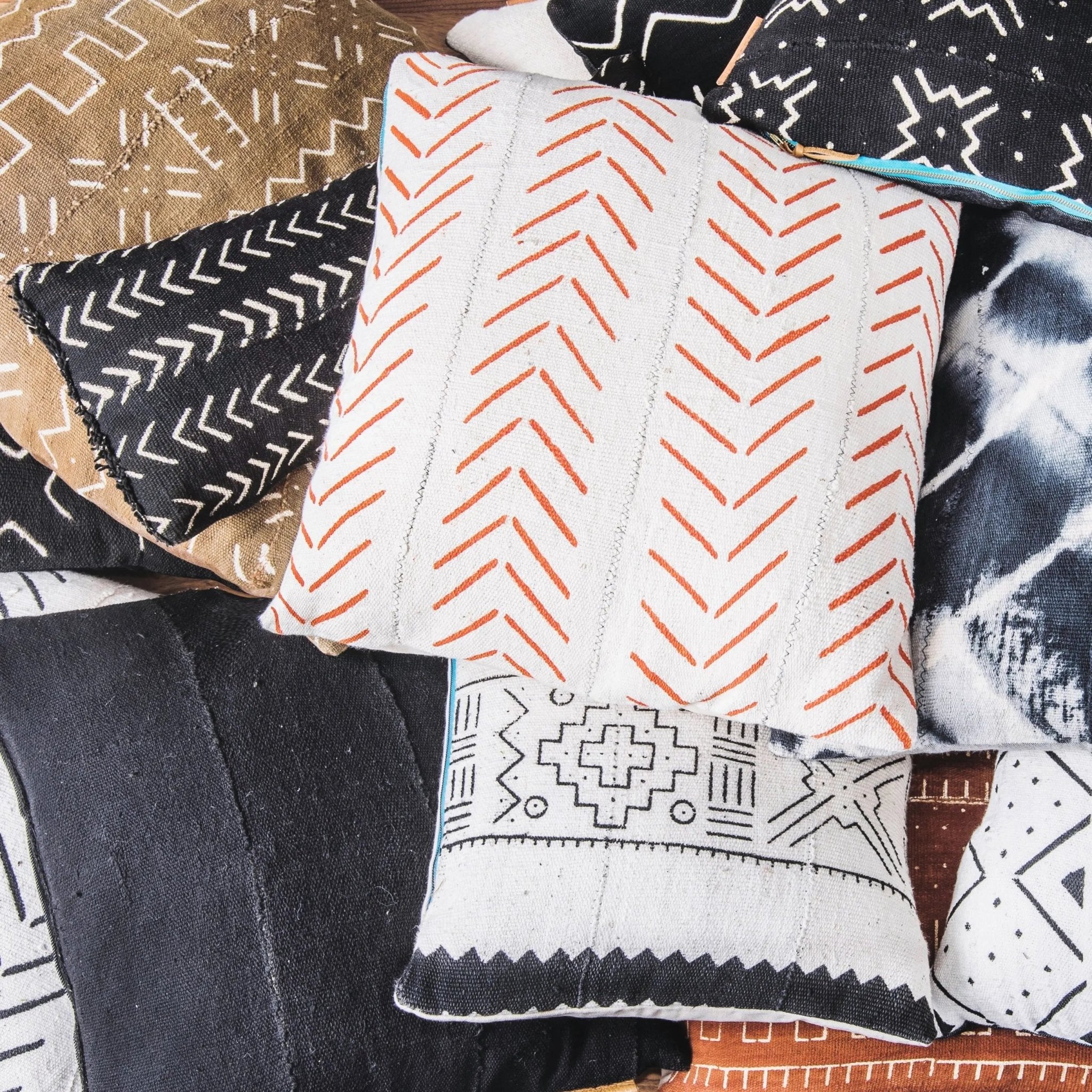 pile of geometric pillows in black white orange and gold with zig zag patterns