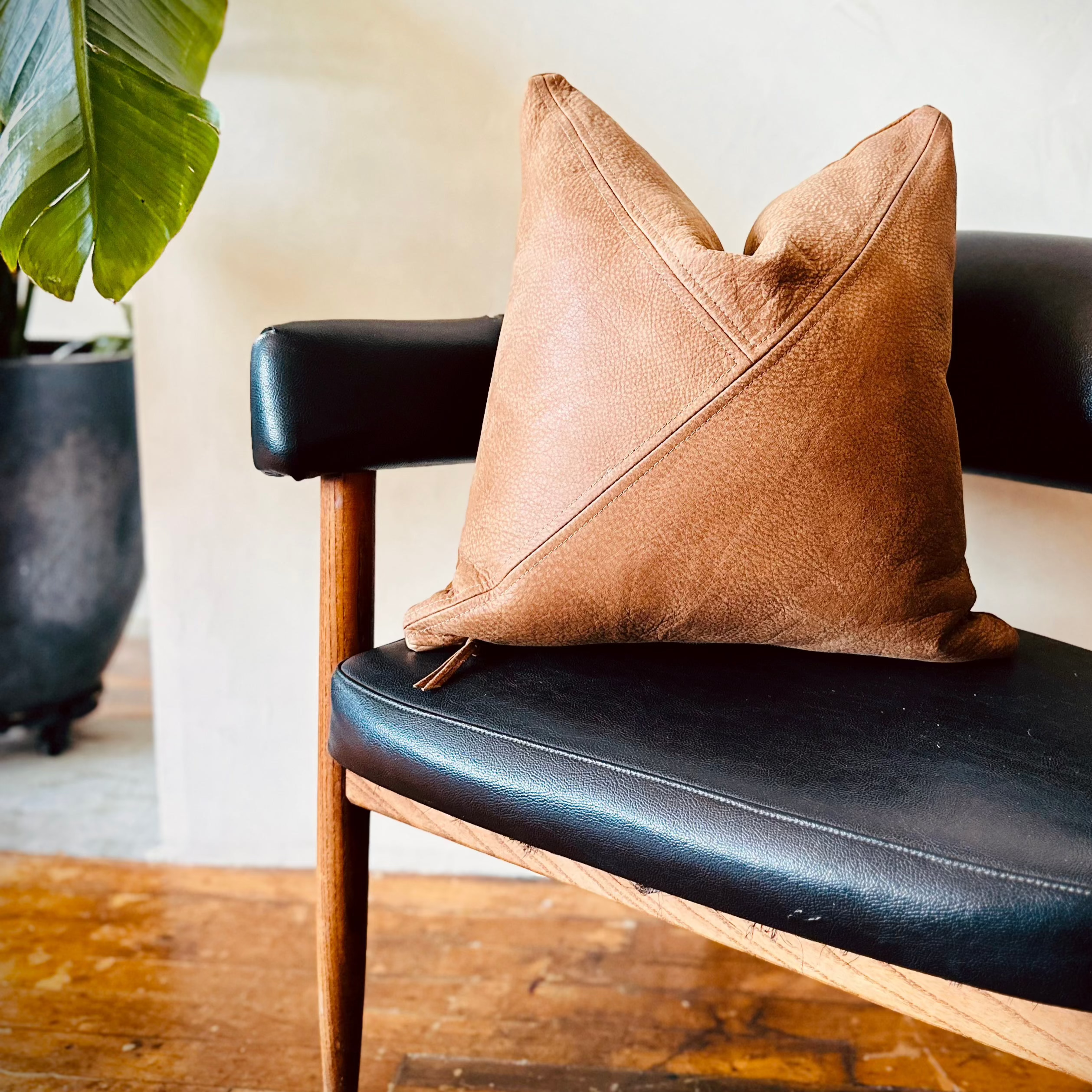 brown leather accent pillow on black chair