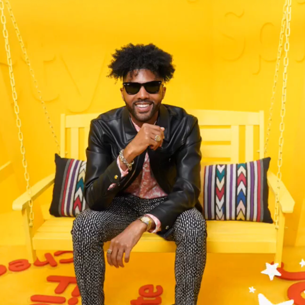 Darius Coleman backstage at the Voice sitting on a yellow swing with HUNTEDFOX pillow