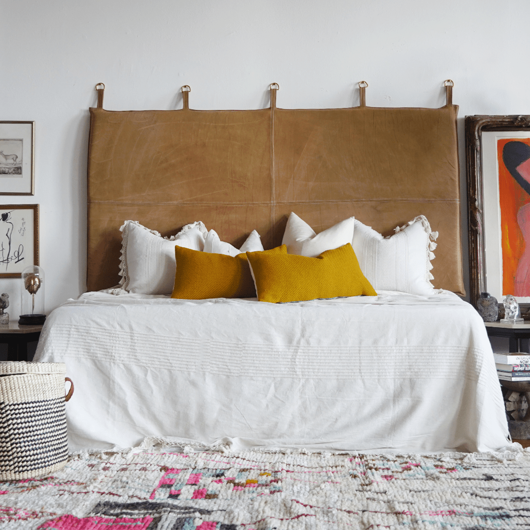yellow pillows styled on white bedding with tan leather headboard