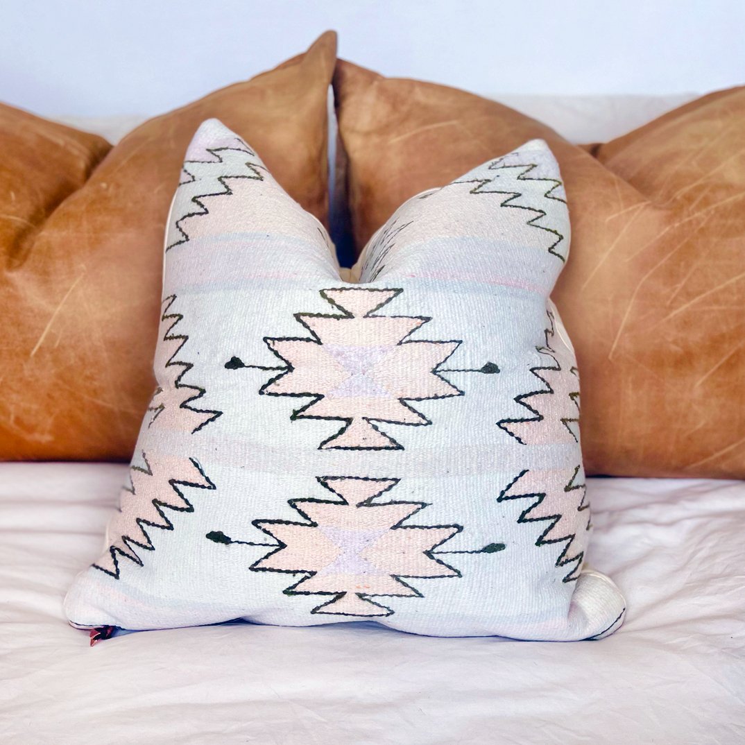 Pastel Pink and Purple Southwestern - baby bluePastelsPillowsHUNTEDFOX - southwestern pink pillow sitting on a bed in front of oversized leather bed pillows