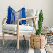 Bright Blue Throw Pillow with Fringe on a white chair with wooden arms